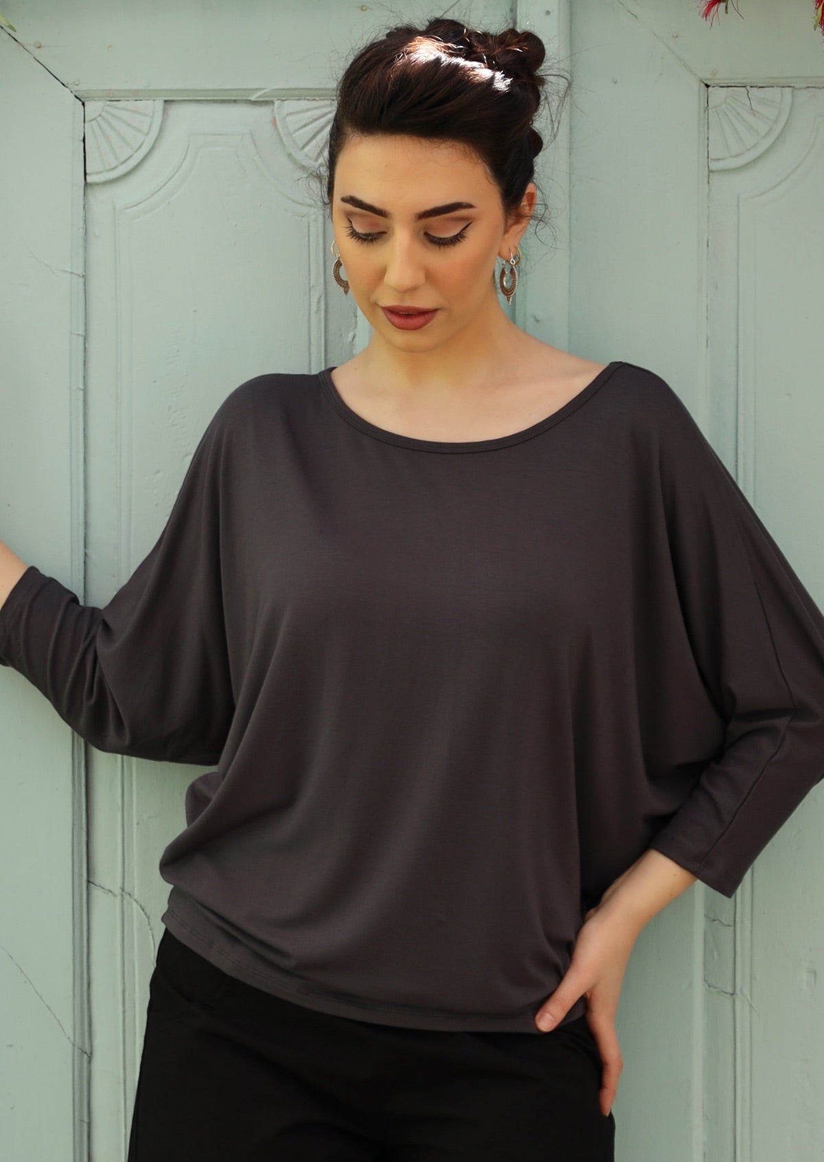 Woman wearing a 3/4 sleeve rayon batwing round neckline dark grey top.