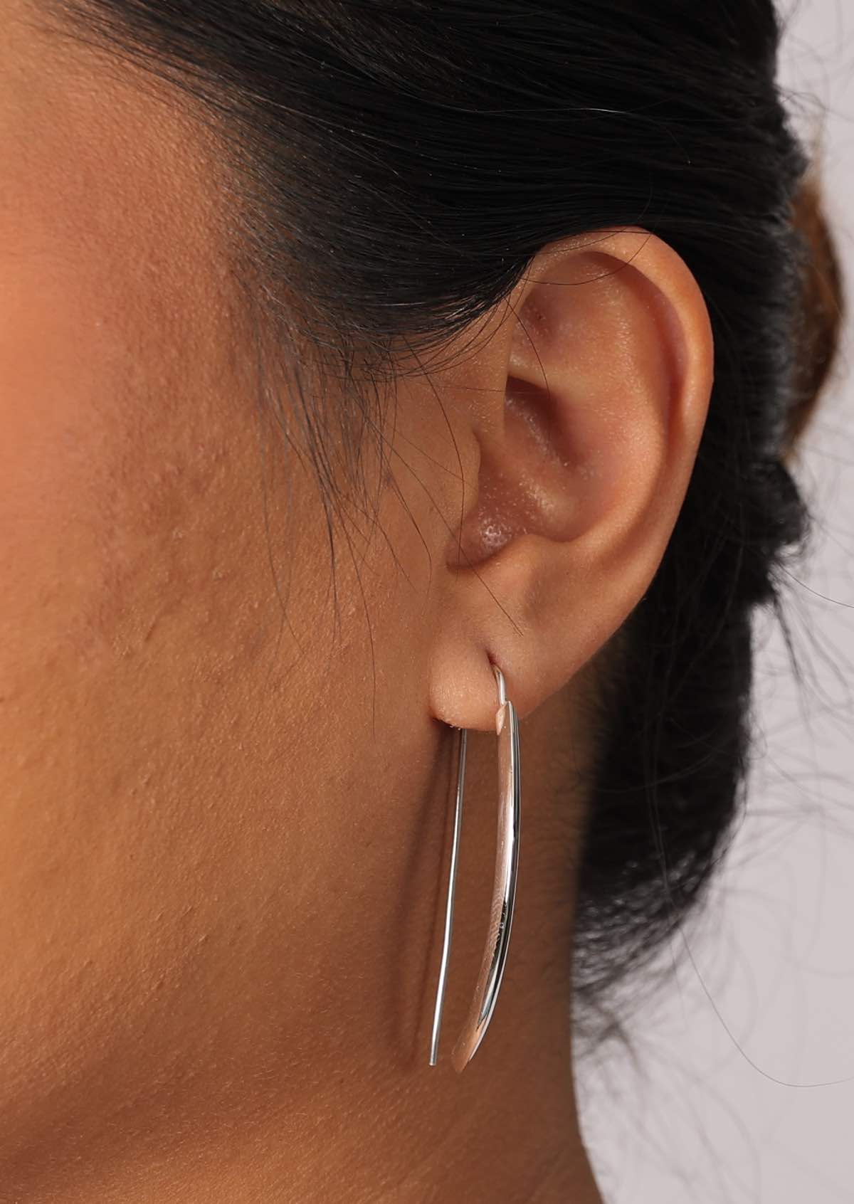 Close up of silver curved earrings with fixed hook and subtle ridge in front