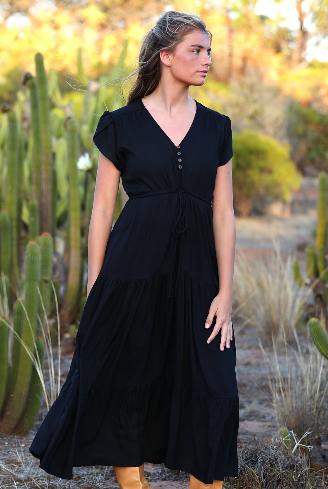 Model wears black rayon maxi dress with tulip sleeves, V-neckline and voluminous skirt