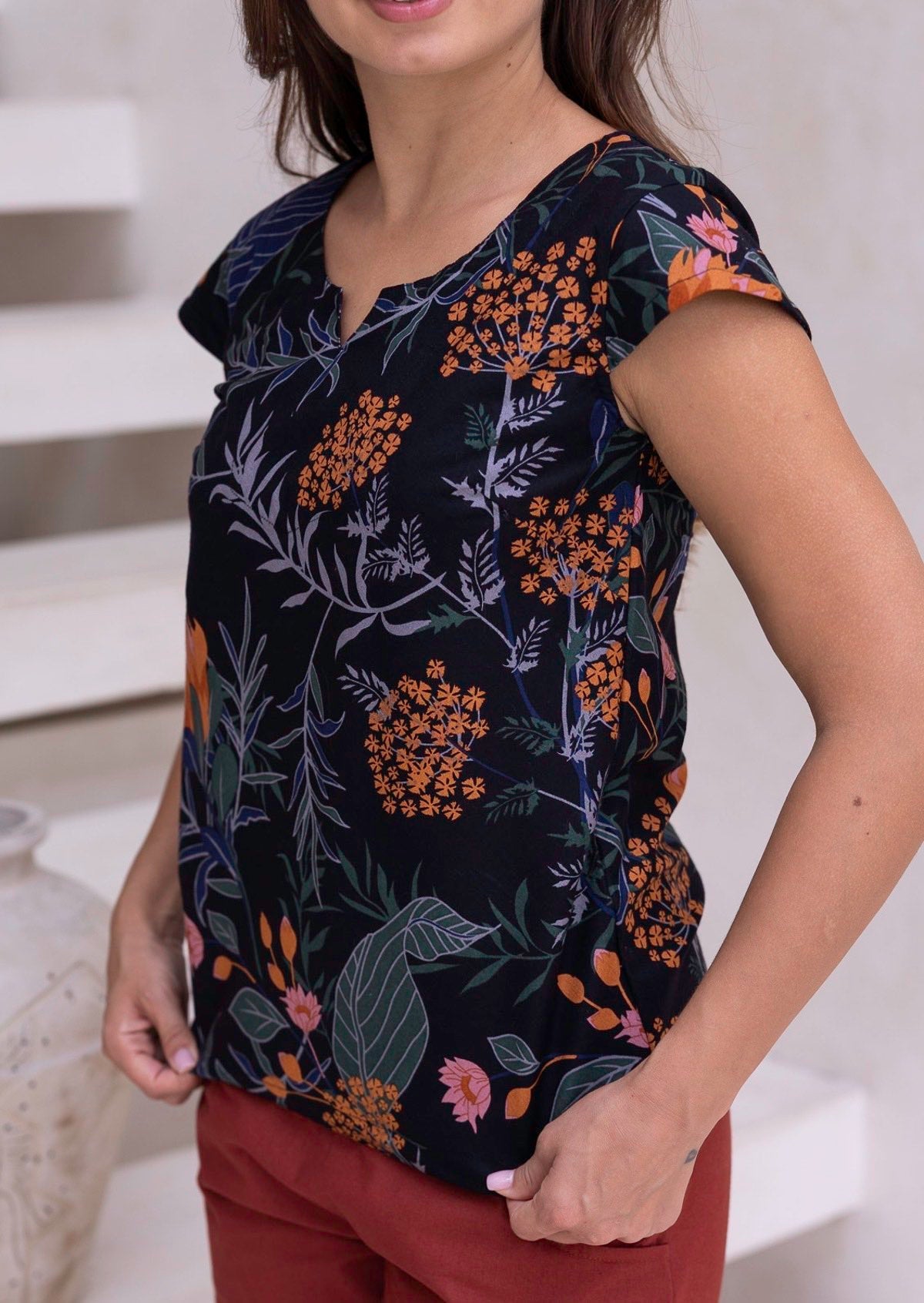 Model wearing a cotton, tailored hip length top with cap sleeves and round neckline with keyhole cutout.