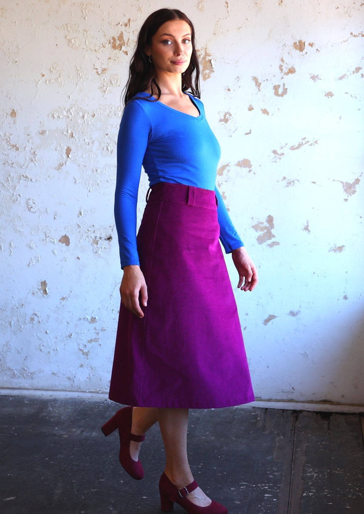 woman wearing purple corduroy aline skirt with belt loops with bright blue long sleeve top