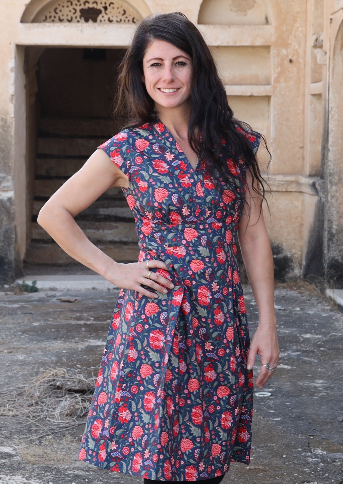 Model smiling with hand on hip wearing deep navy blue based floral cotton retro style dress