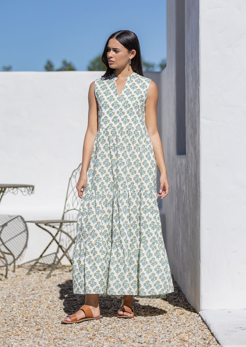 Woman wearing a sleeveless white cotton maxi dress with a floral pattern outdoors.