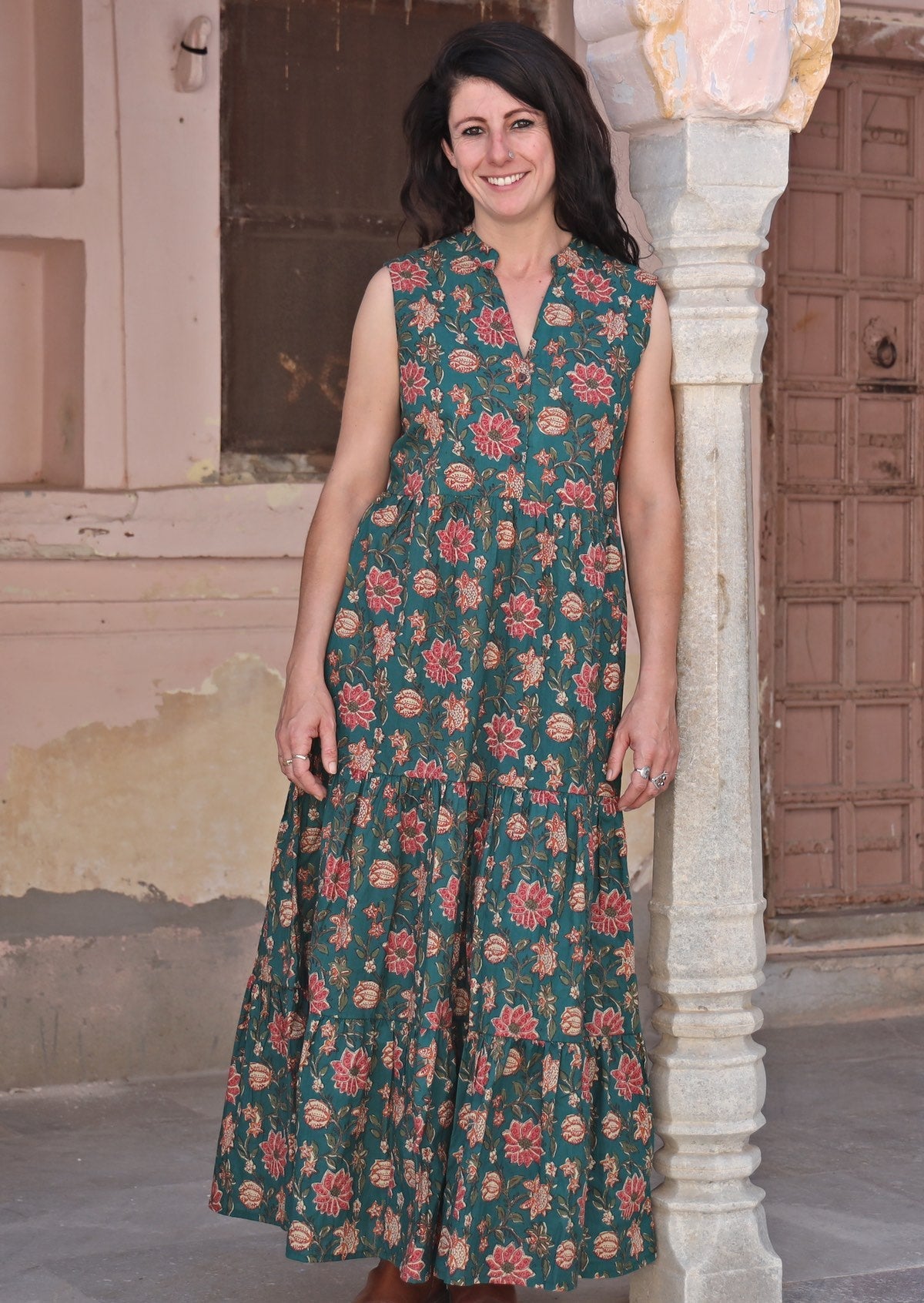 Model standing in sleeveless maxi dress with buttoned bodice and mandarin collar forming V neck.
