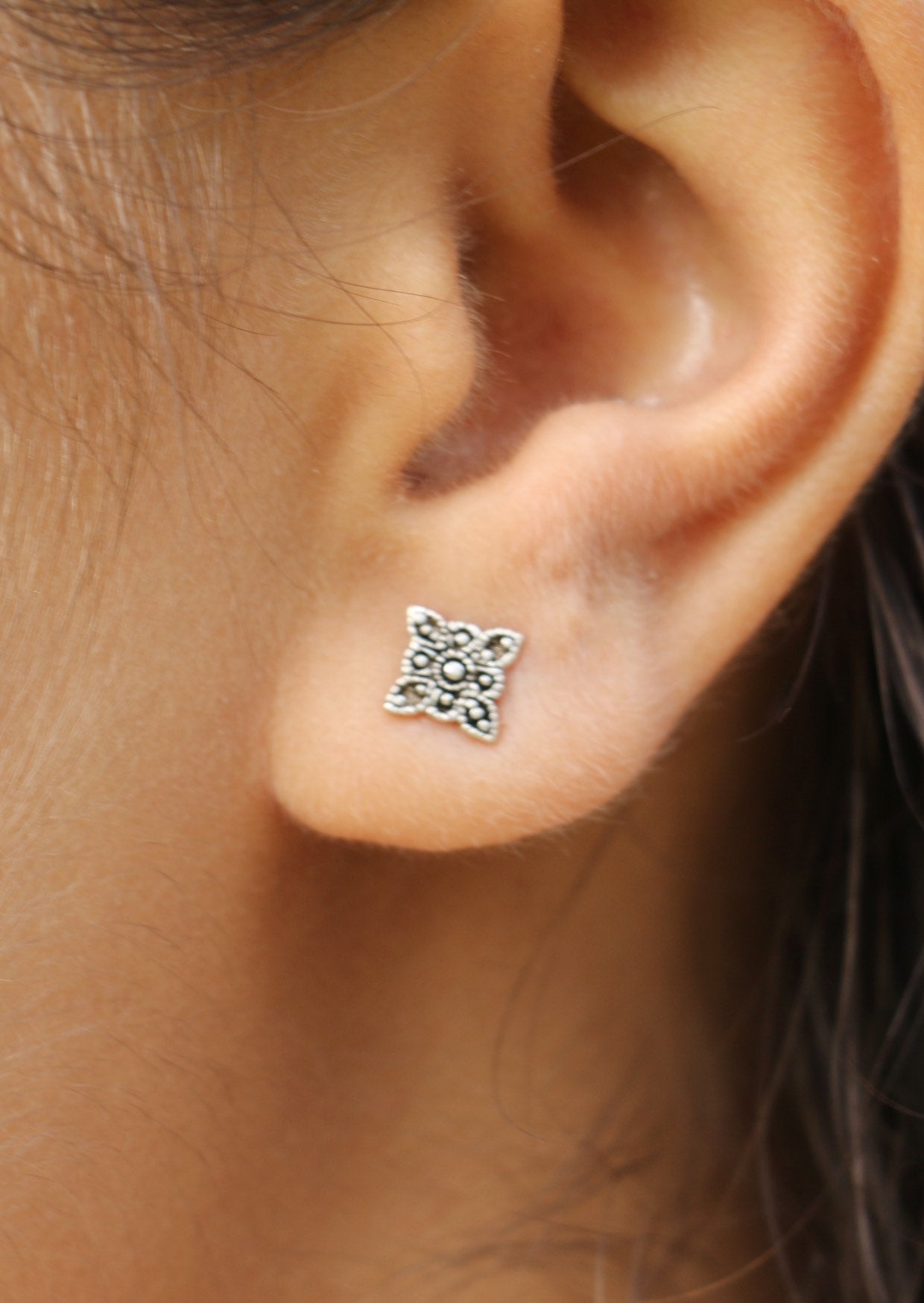 Woman wearing delicate Boho Blooms silver studs with intricate floral design and secure butterfly backs