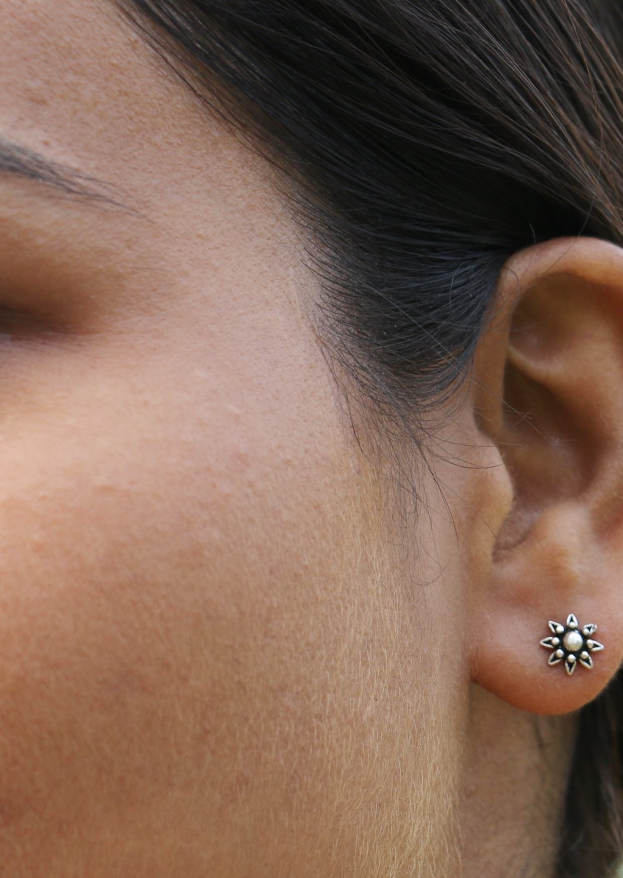 Woman wearing Silver Flower Studs with intricate floral design and secure butterfly backs