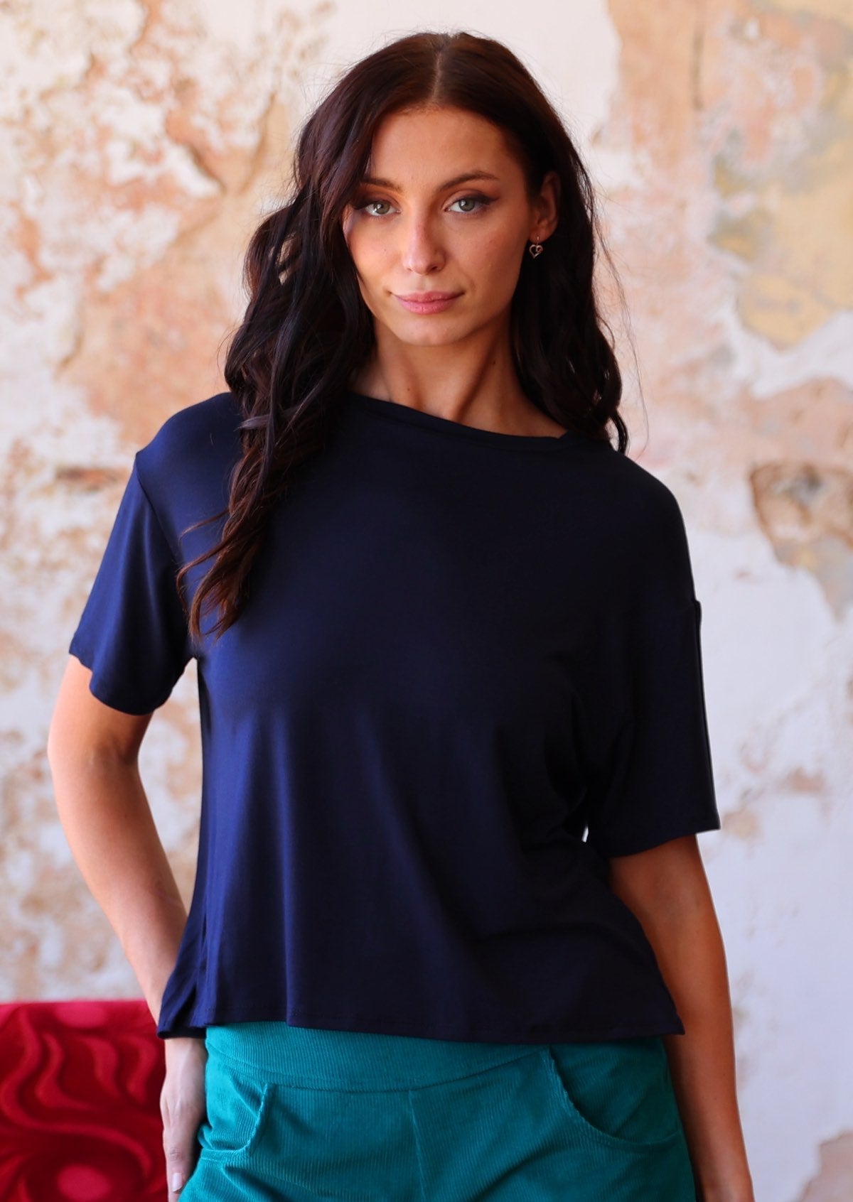 woman in navy blue loose fit t-shirt over teal corduroy pants