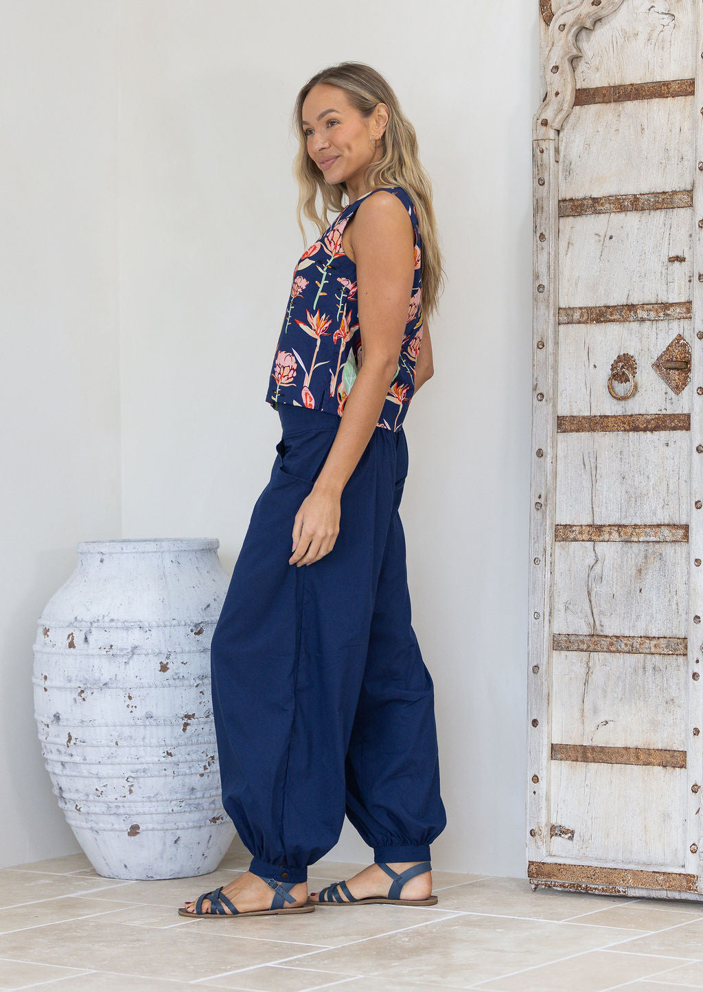 Woman wearing a navy blue floral sleeveless top with a straight edge hem and bust darts