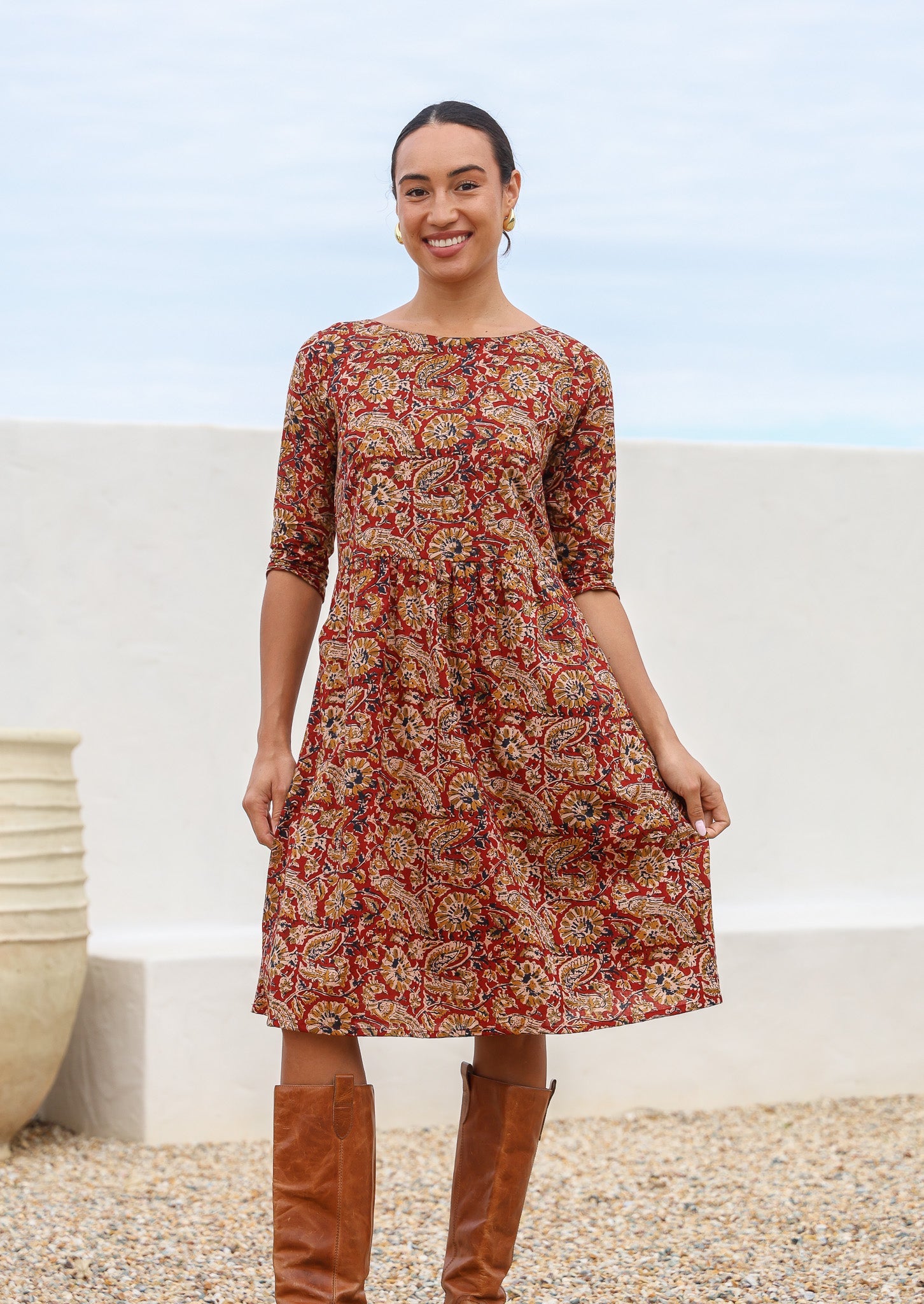 100% cotton knee length dress in earthy floral print on warm red base with 3/4 sleeves, round neckline and pockets.