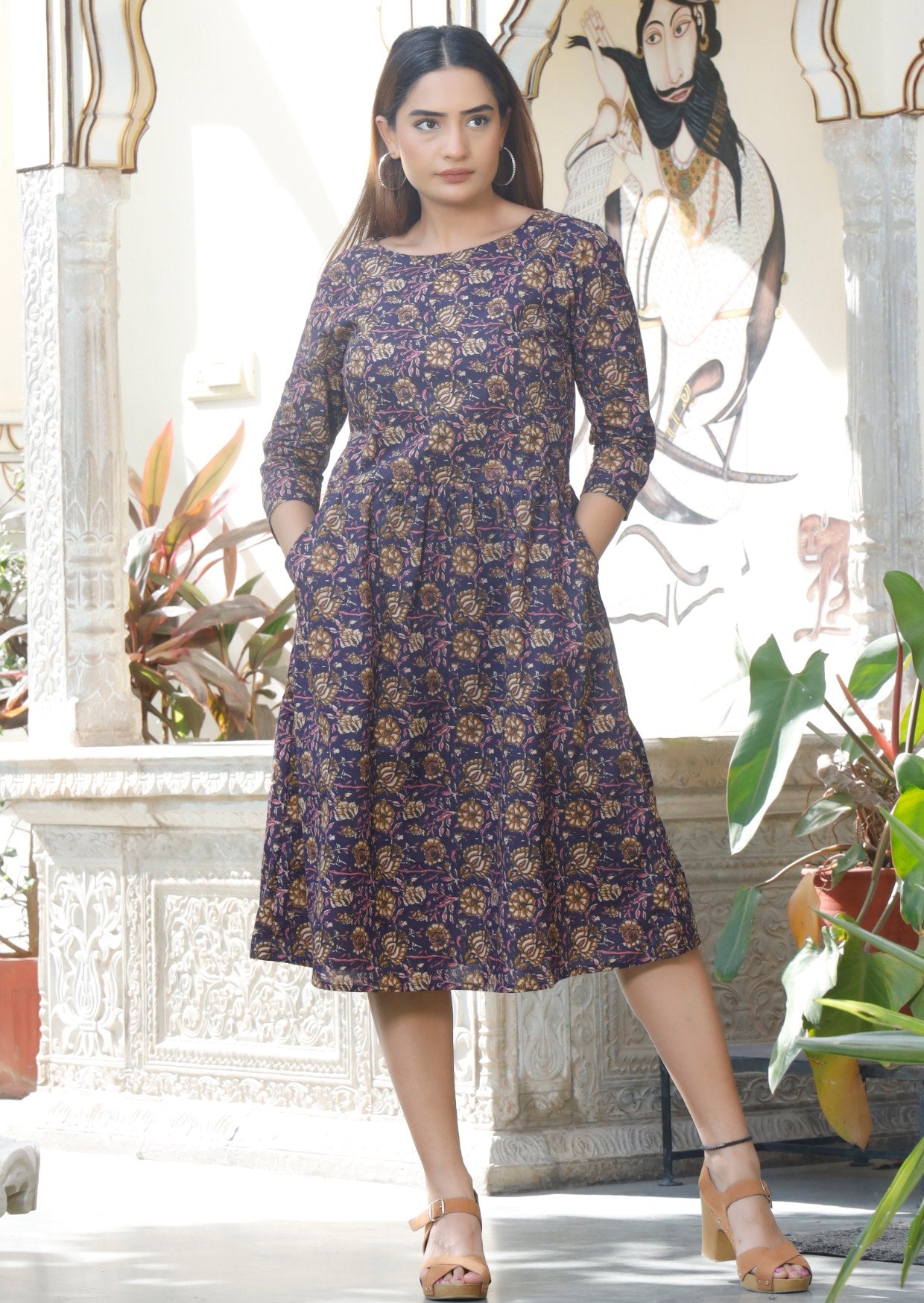 Model wearing relaxed fit cotton dress sitting just below the knee length with wide round neckline and hands in pocket.