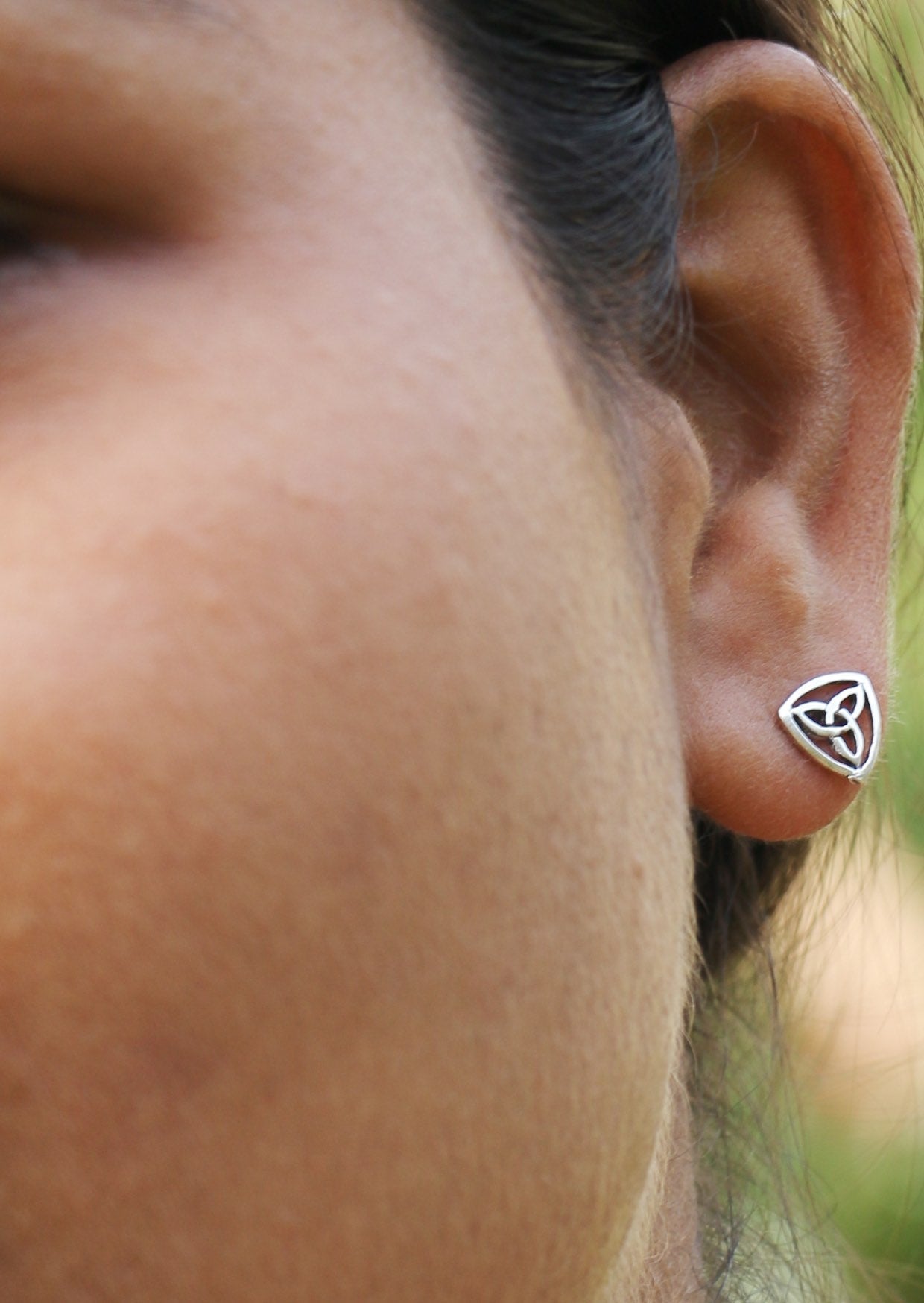 Close up of a woman wearing a Celtic triangle studs with intricate design.