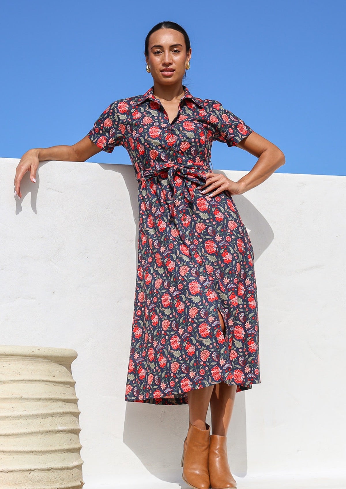 Woman wears 100% cotton button through shirt style dress with collar and short sleeves, in bright red floral print.
