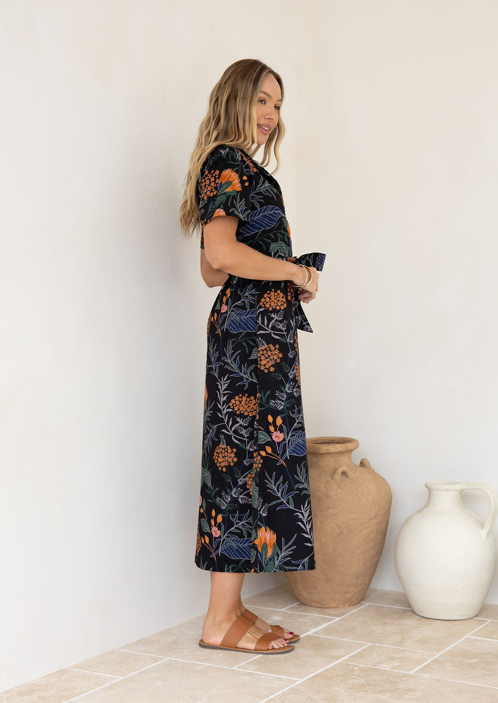 Woman wearing cotton shirt dress with collar and T-shirt sleeves, with hands in holding the fabric tie.