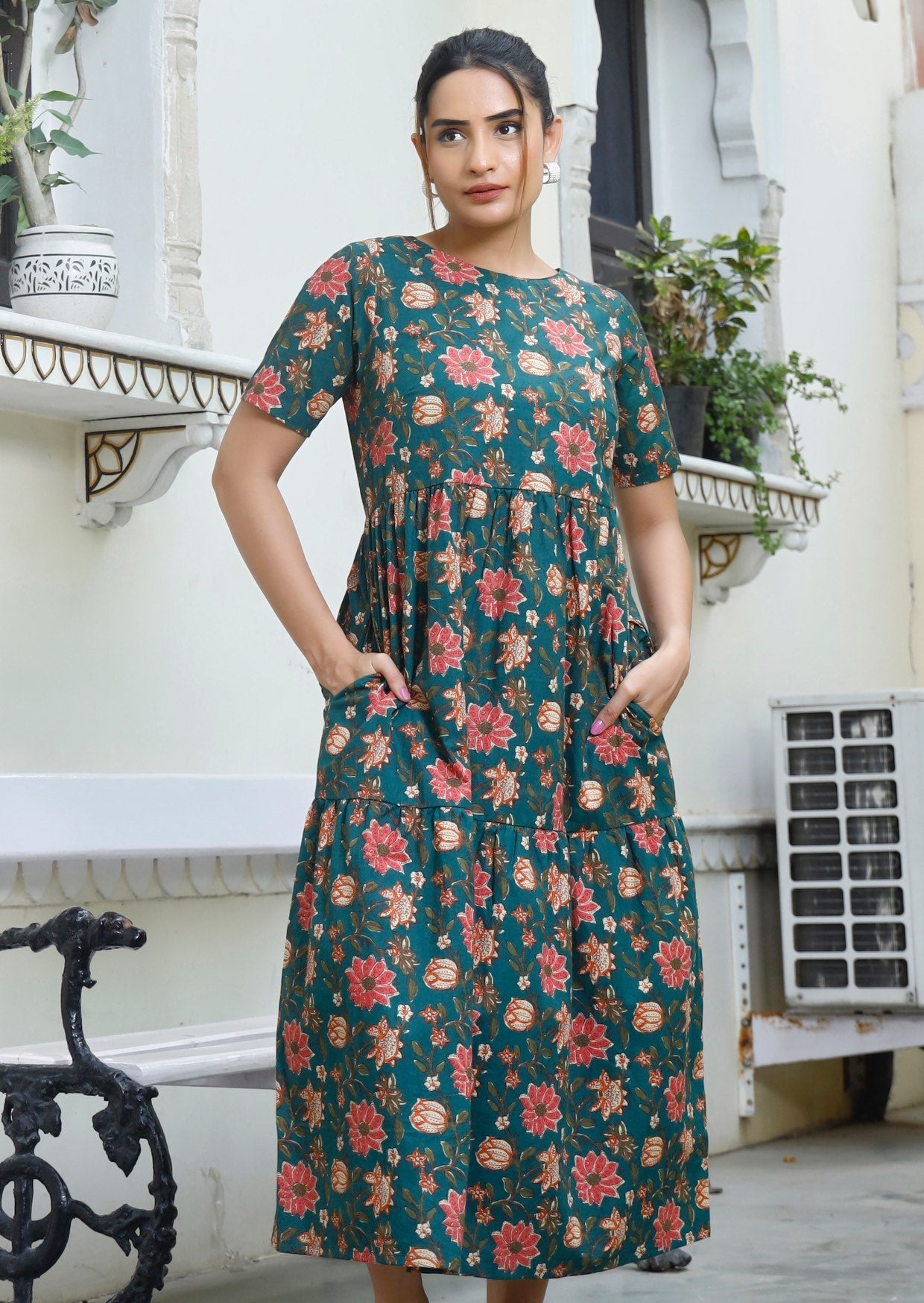 Model wears 100% cotton midi length short sleeve dress in vibrant pinkish floral print on deep green base.