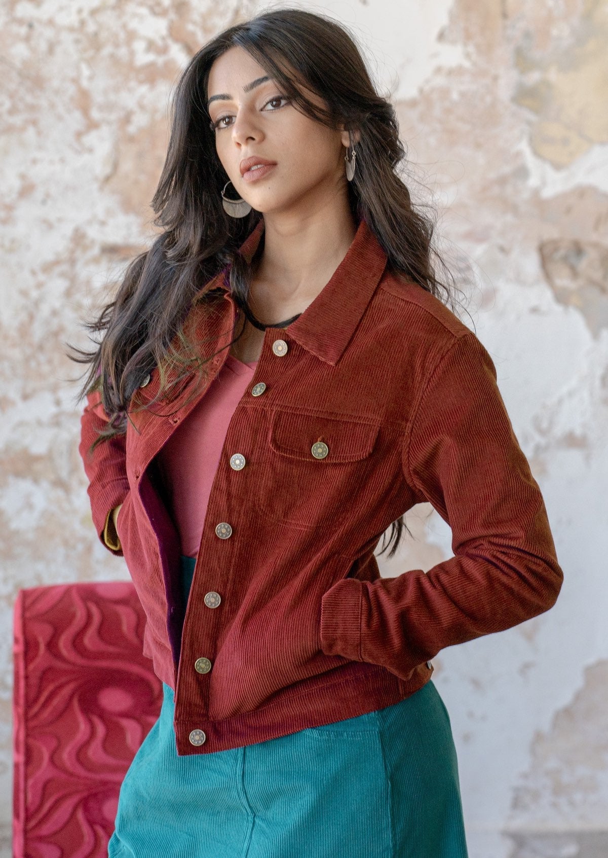 woman wears rust coloured cotton corduroy jacket over teal corduroy skirt