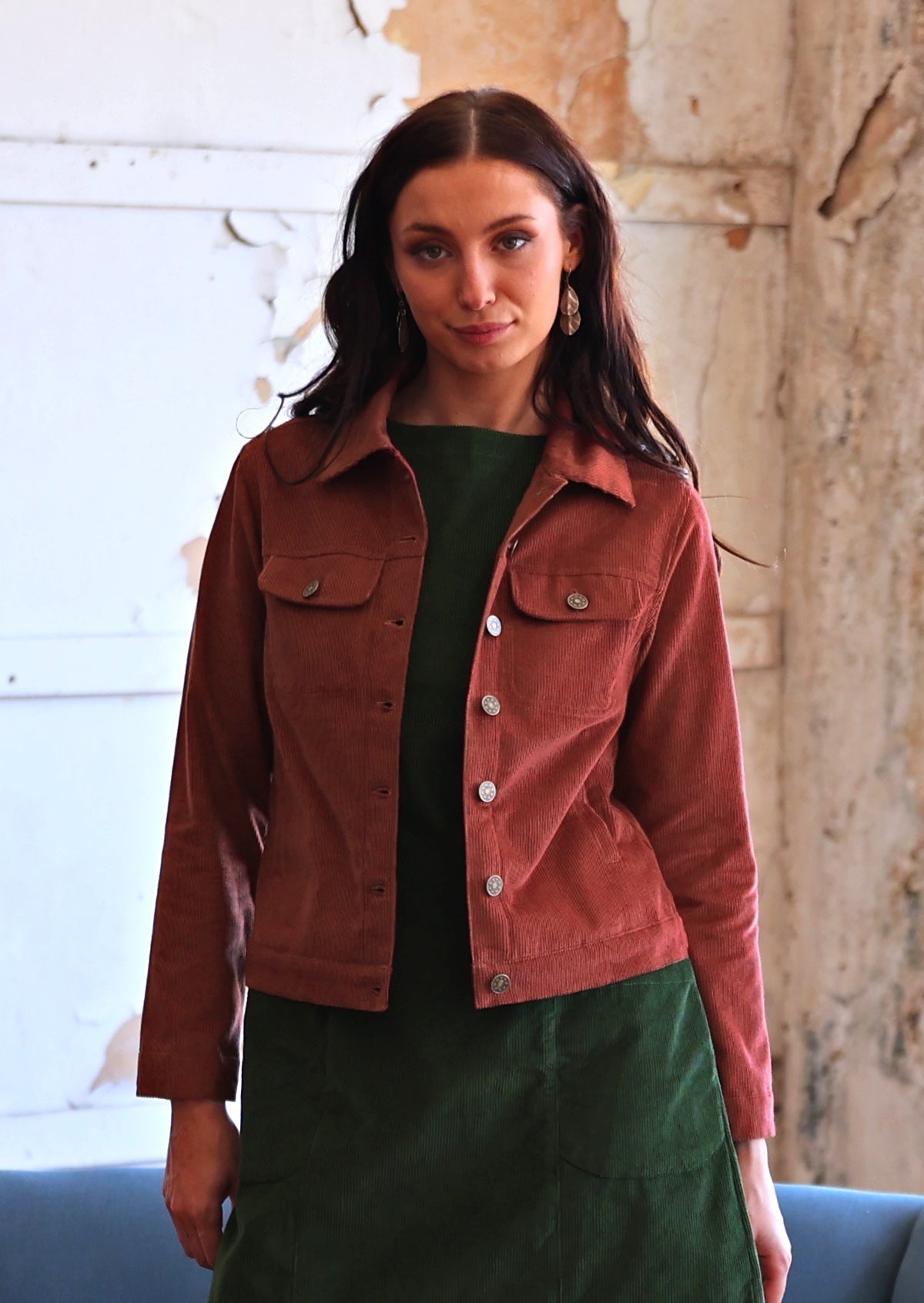 Woman in rust coloured cotton corduroy jacket over green corduroy tunic and leggings