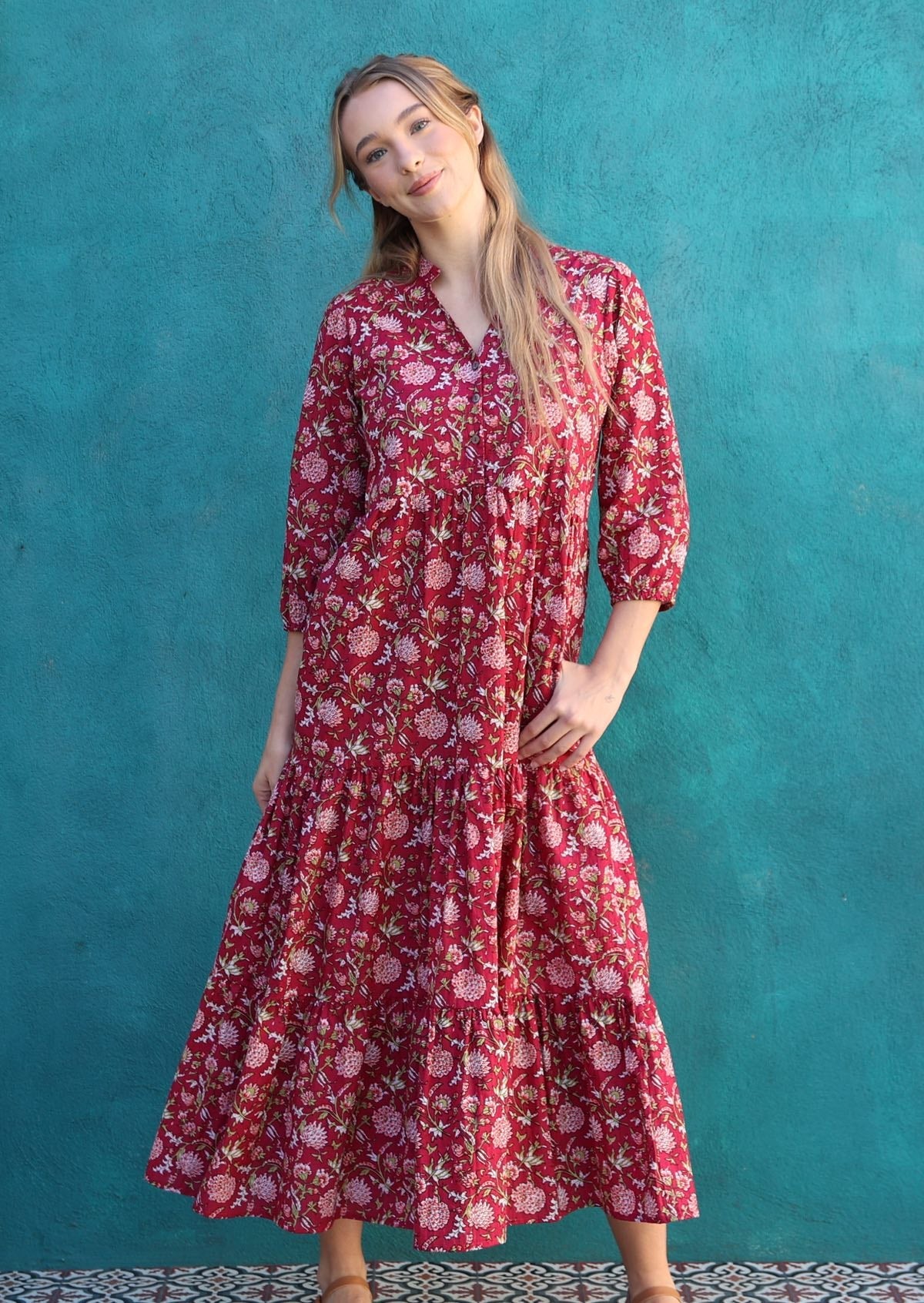 Woman poses in cotton maxi dress with tiered skirt, buttoned bodice. 3/4 sleeves and hidden side pockets