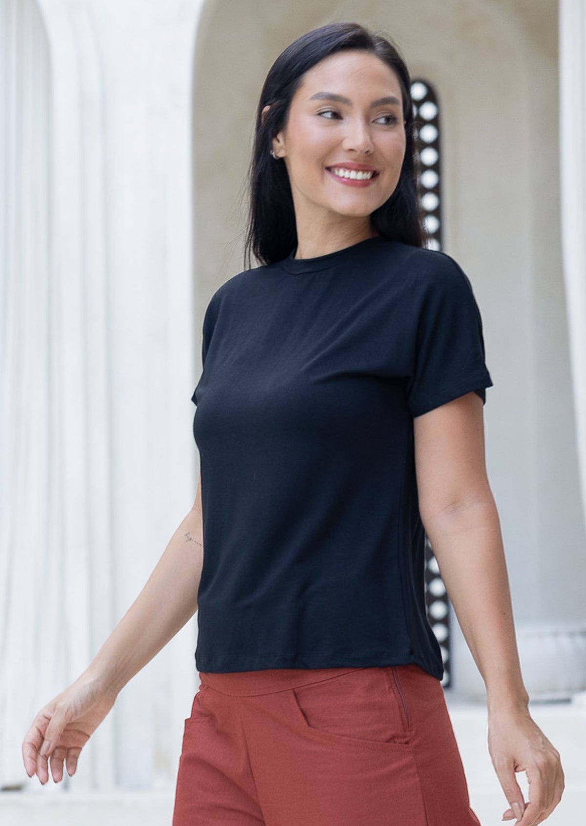Woman wearing a black stretch rayon crewneck t-shirt and rust pants with pockets