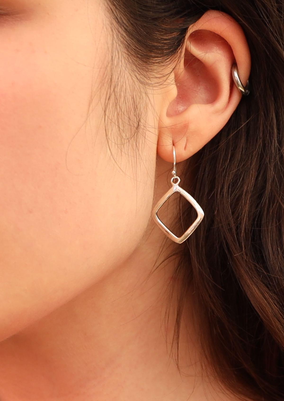 Model with dark hair wearing geometric shaped silver earrings