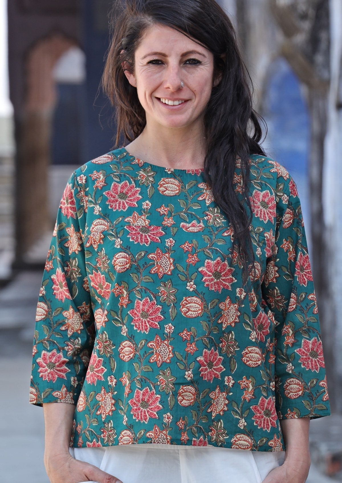 Woman wearing relaxed fit cotton top with 3/4 sleeves and round neckline in green with a floral print