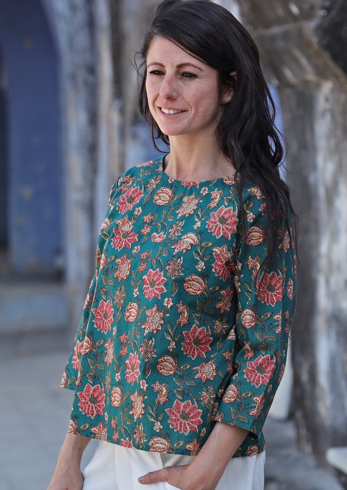 Woman stands sideways in 100% cotton loose fit top with 3/4 sleeves and round neckline