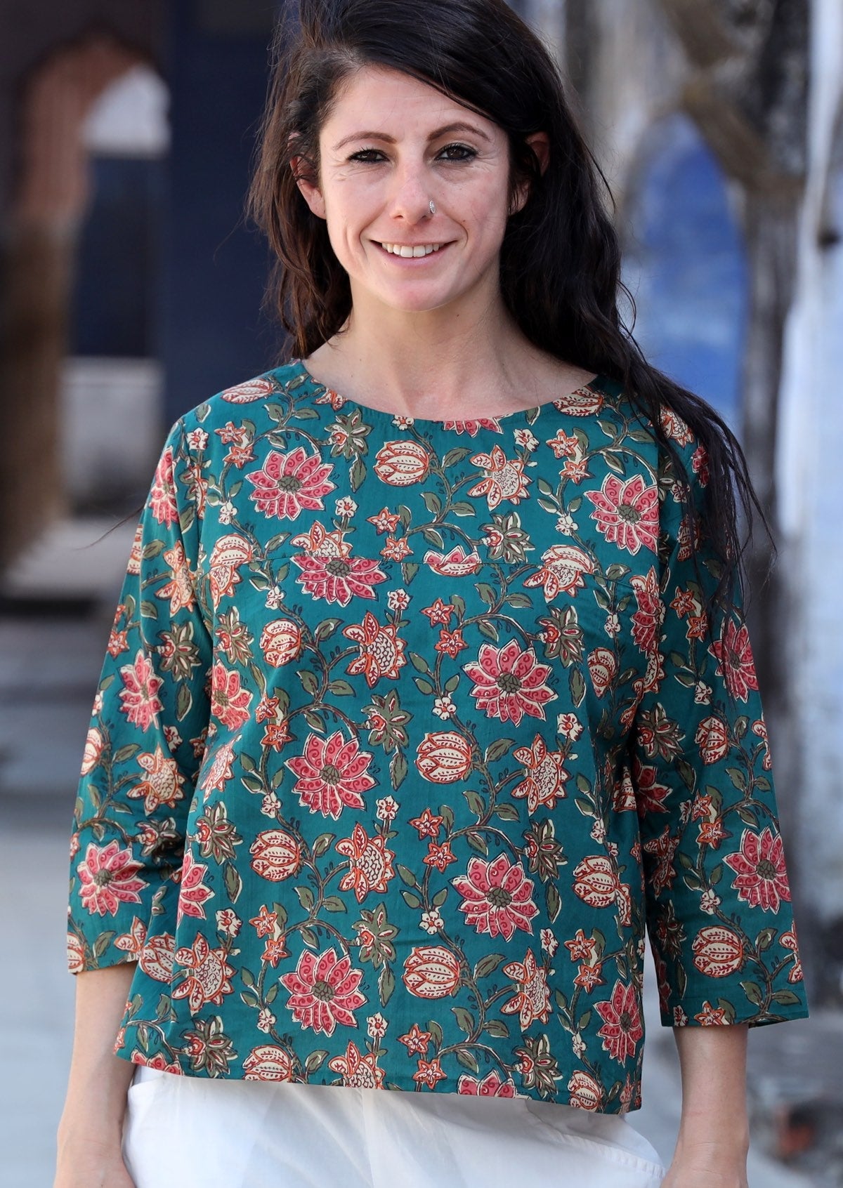 Model wearing relaxed fit cotton top with 3/4 sleeves and round neckline in green and floral print