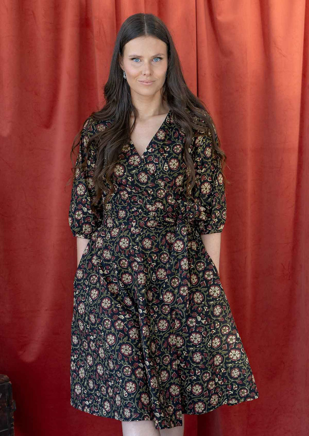 Model wears a 100% cotton, midlength wrap dress with V neckline, pockets, 3/4 sleeves and a wide waist-tie