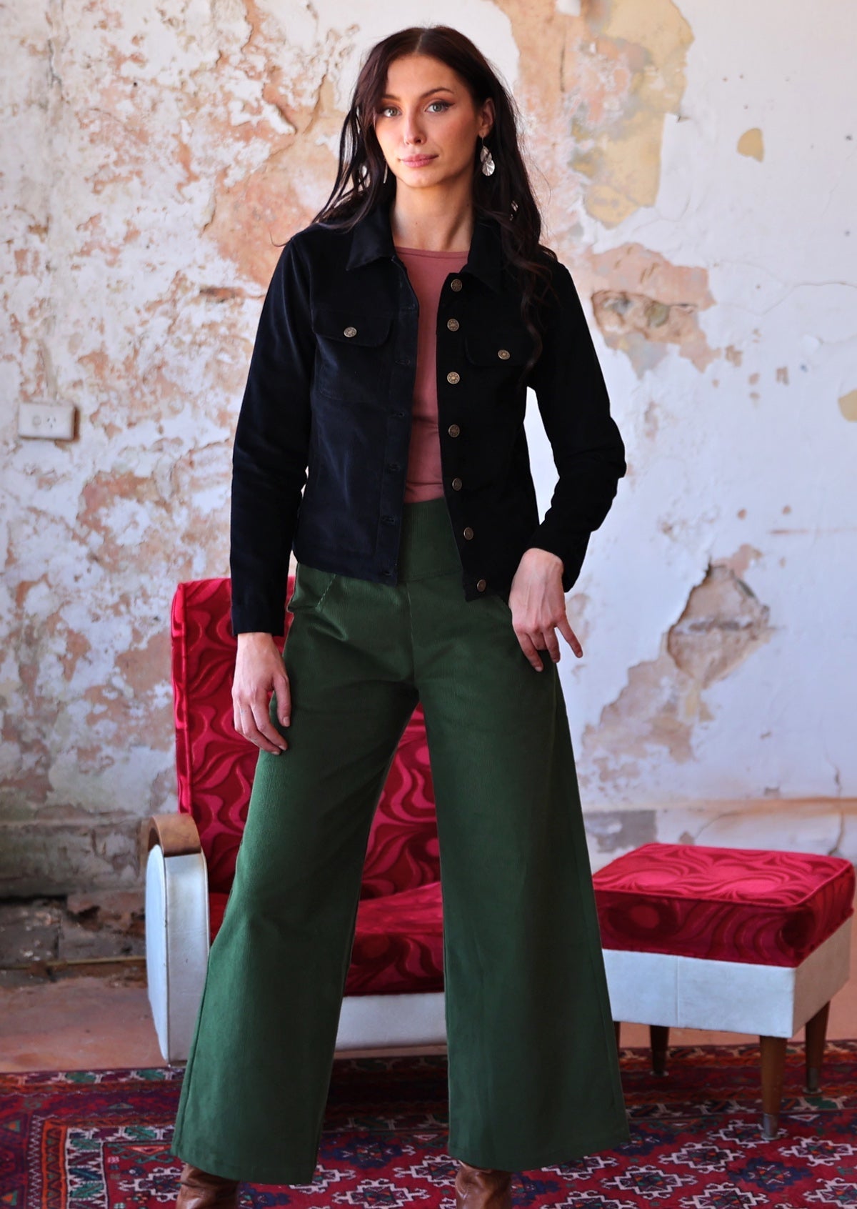 woman wearing long sleeve pink boat neck top and green corduroy pants with black corduroy jacket over the top