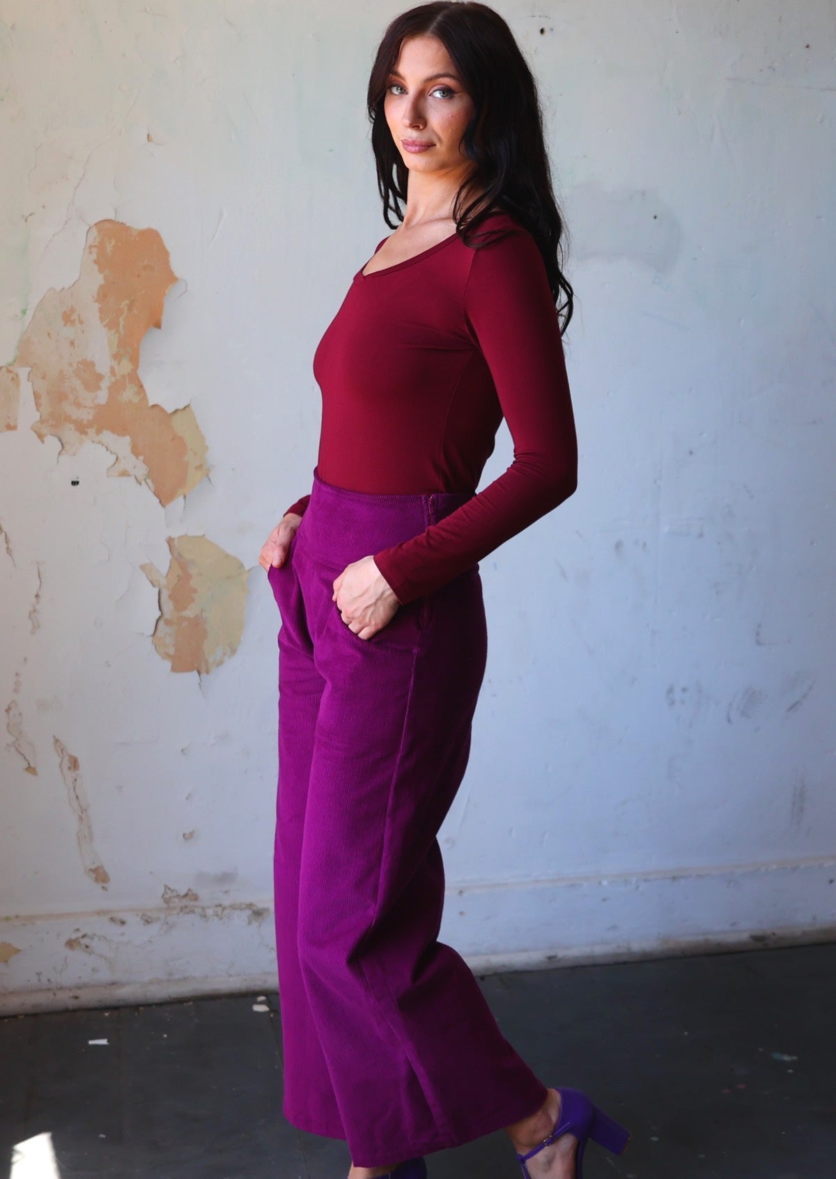 Model stands side on in corduroy wide leg pants with a side zip, with her hands in pockets