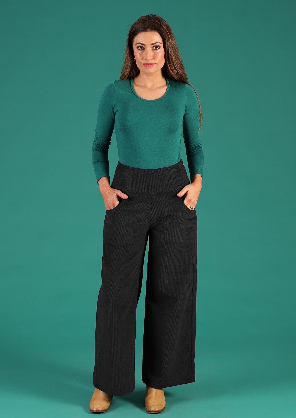 Woman wears corduroy wide leg pants with wide waistband, a side zip and pockets