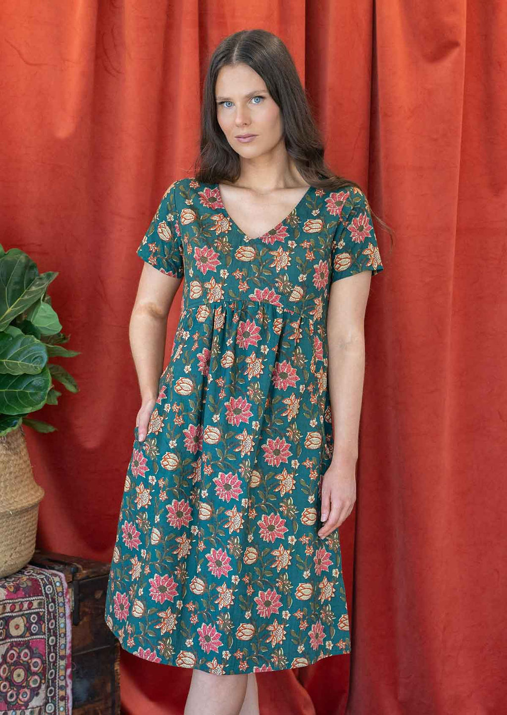 Model wearing a cotton V-neck short sleeve dress with empire waistline and  hand in pocket.
