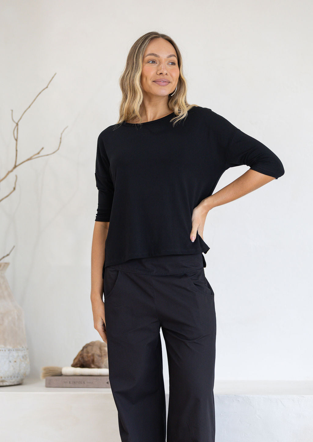 Woman wearing a relaxed fit black top with 3/4 sleeves with hand on hip