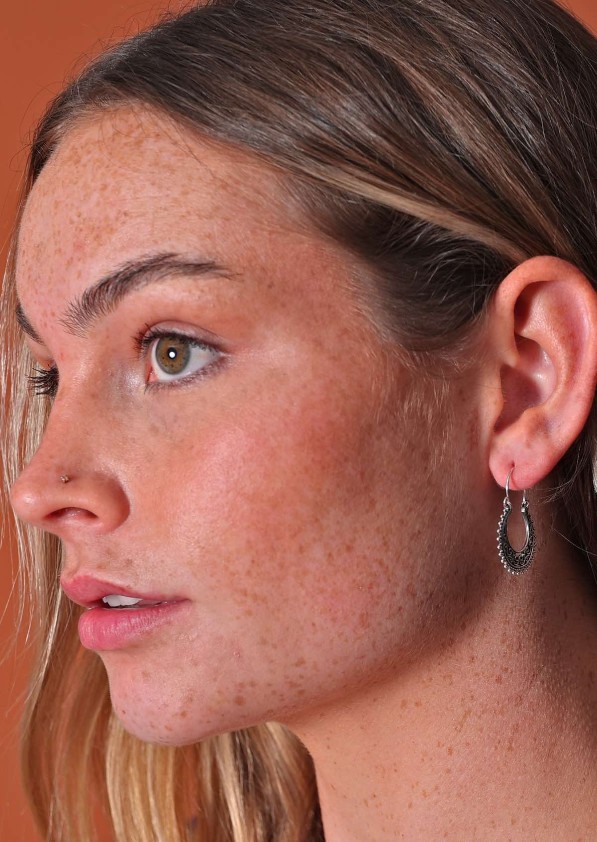 Woman wears silver lacy filigree hoop earring with wire hook