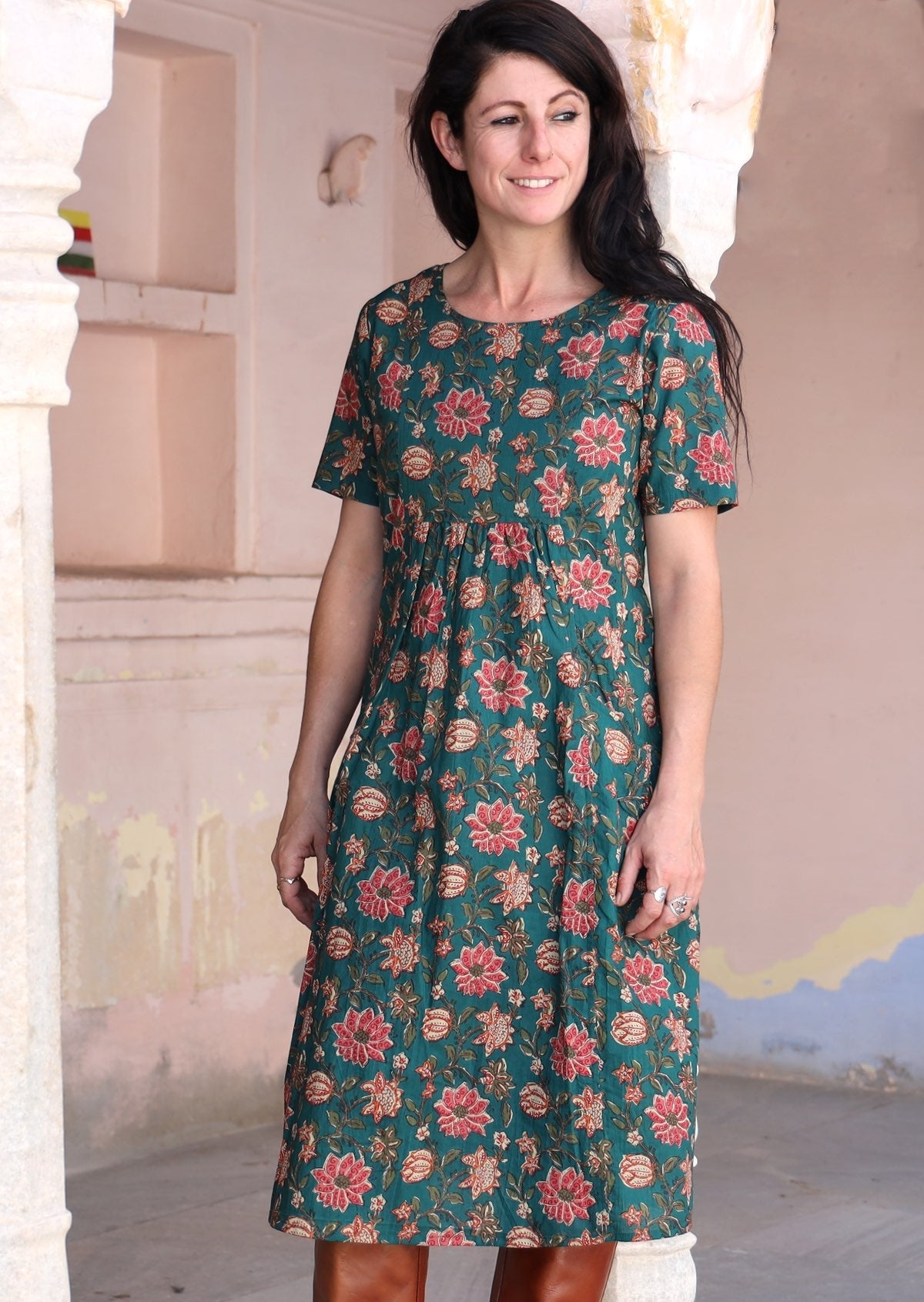 Model wears relaxed fit, knee length cotton dress with short sleeves and gathers under the bust.