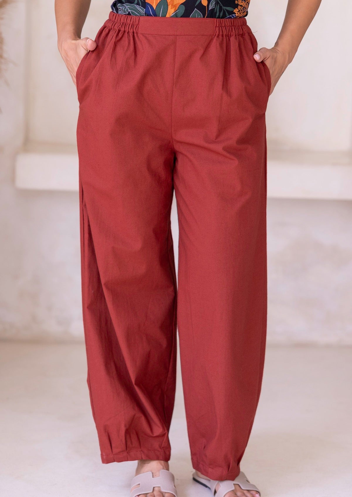 100% cotton boho-style wide-leg pants in rust, featuring pockets, pleated ankles, and elastic on both sides of the waist