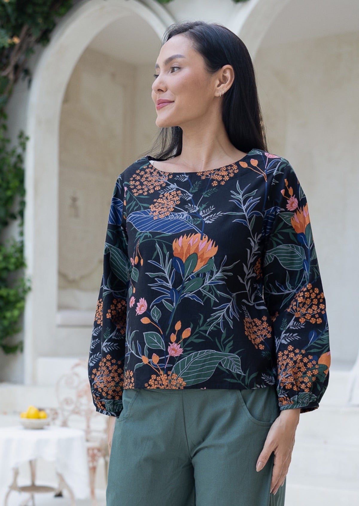 Woman is wearing loose fitting bishop sleeves 100% cotton top with boat neckline in gorgeous queen protea print