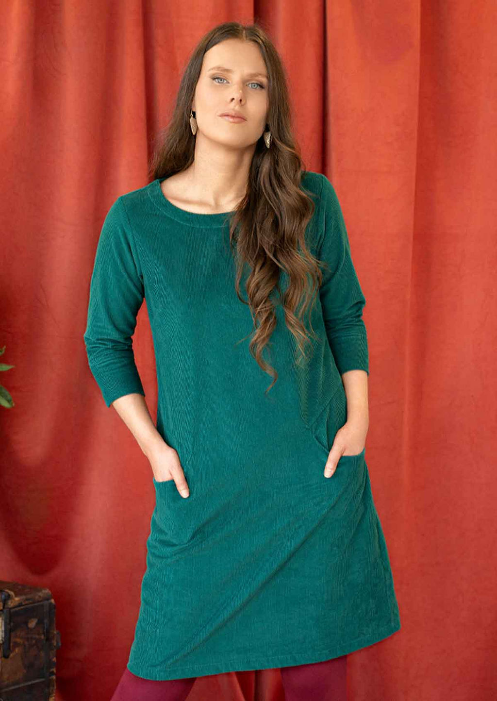 Woman wearing teal corduroy dress over leggings hands in pocket