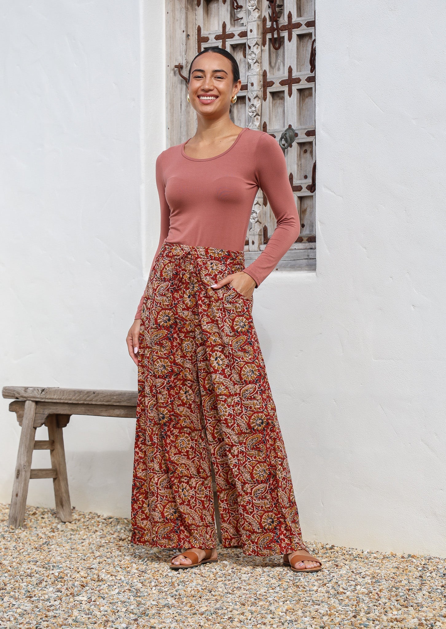 Model pairs wide leg 100% cotton, floral printed pants in earthy tones with round neck stretch top in dusty rose.