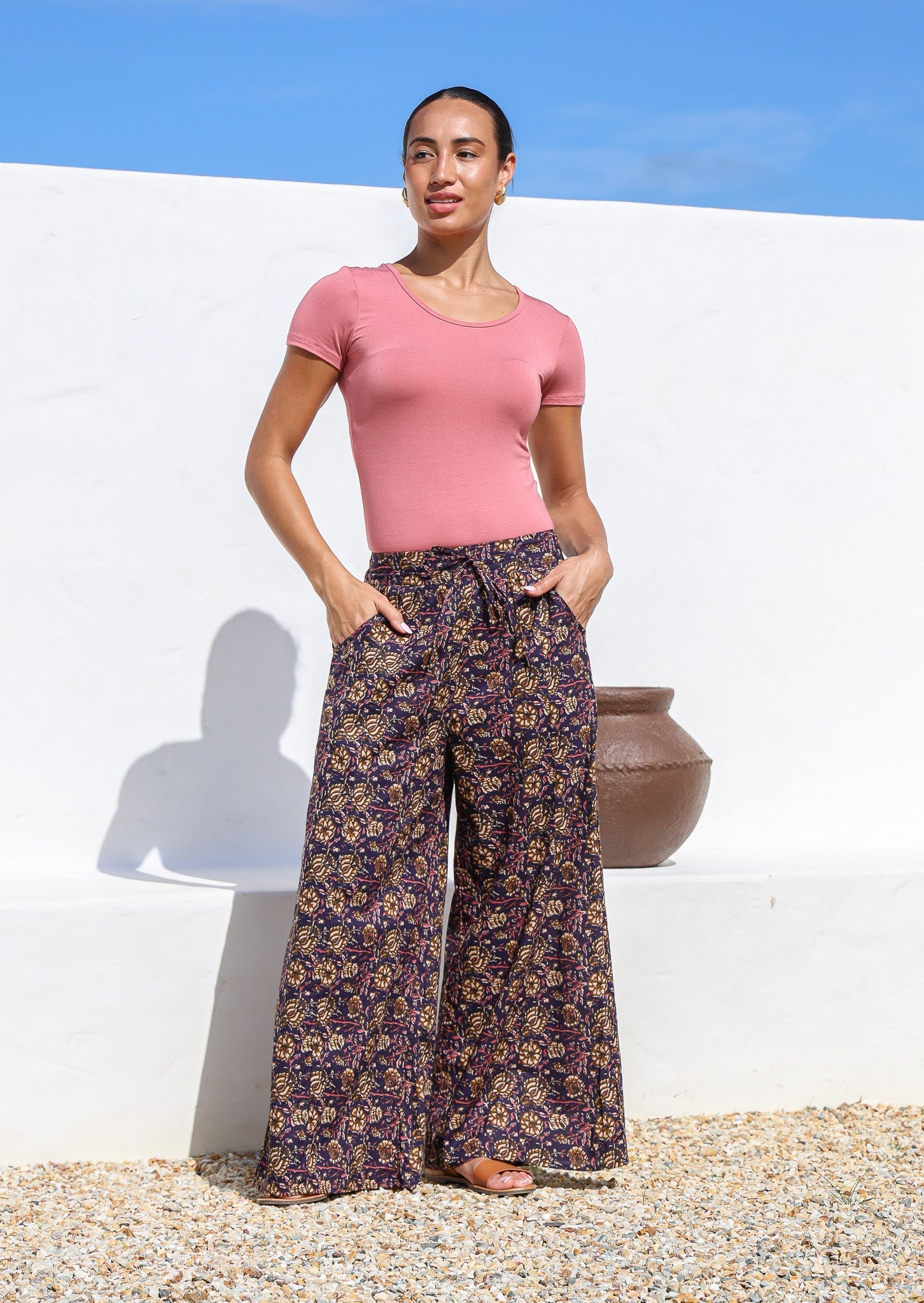 Model wears wide leg cotton floral printed pants with drawstring and hand in deep pockets.