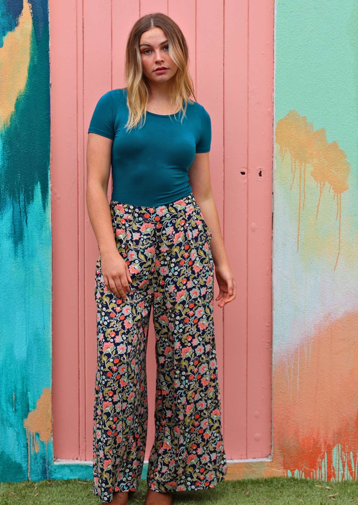 Woman wears multicoloured floral on dark blue base non-stretch rayon wide leg pants