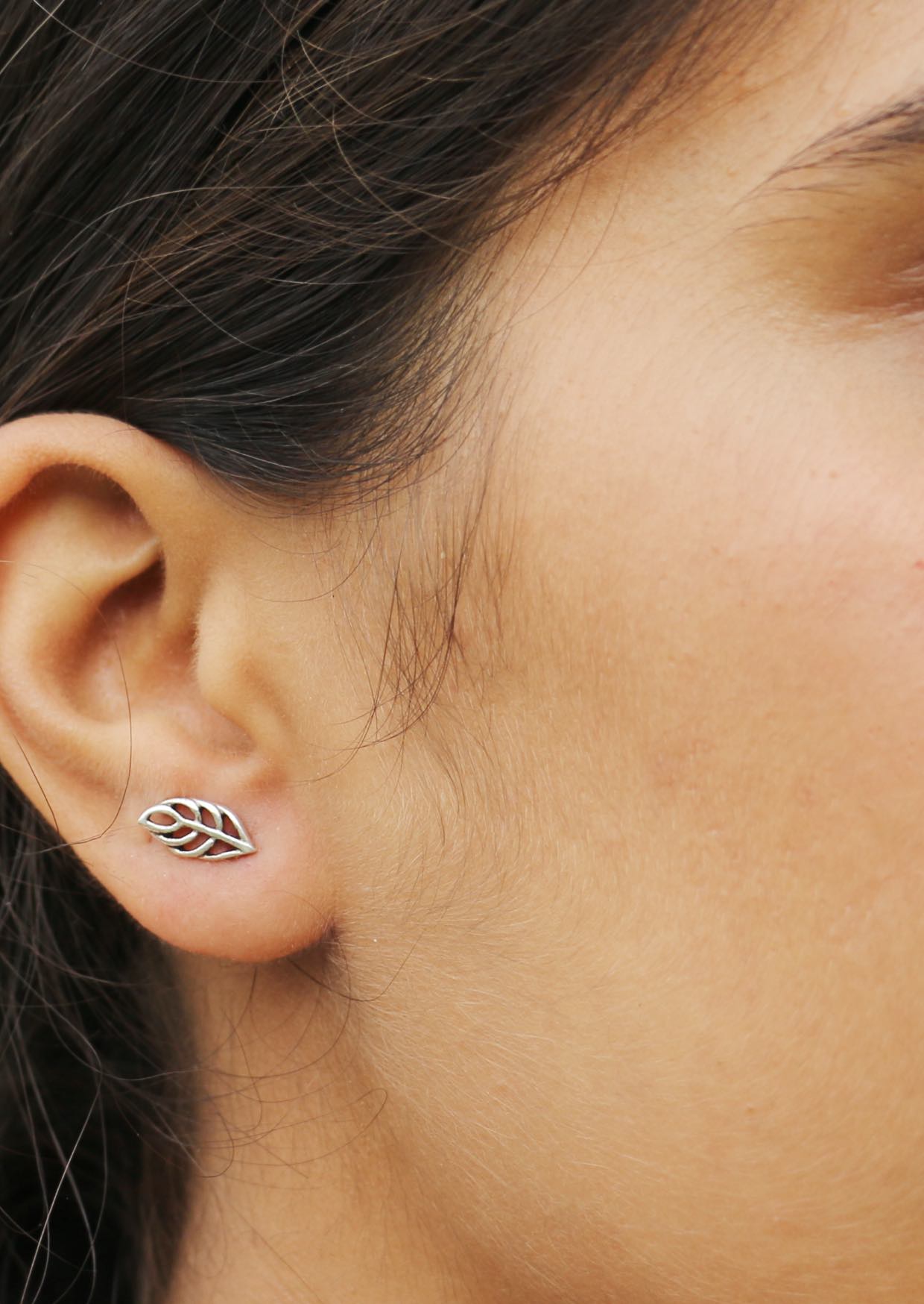Close-up of an ear wearing a sterling silver leaf-shaped studs with butterfly backs