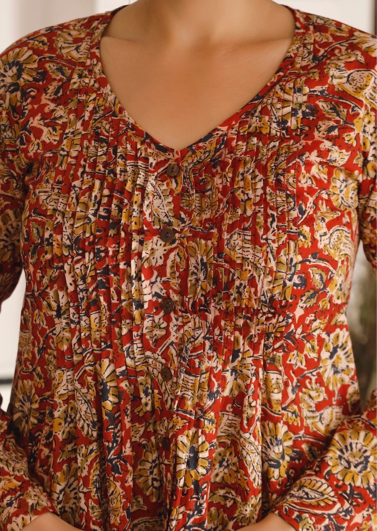Close image of delicate floral print top in earthy tones with button through style and pin tucks across the chest.