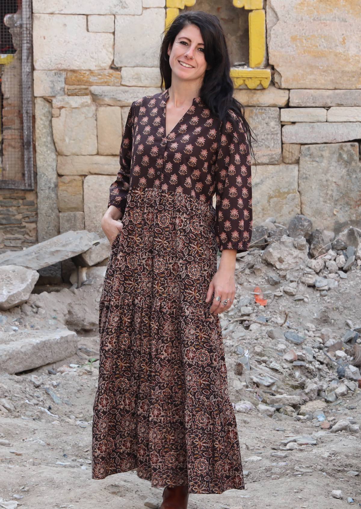 Model wears dark brown based floral cotton dress with pockets, 3/4 sleeves and V neckline.