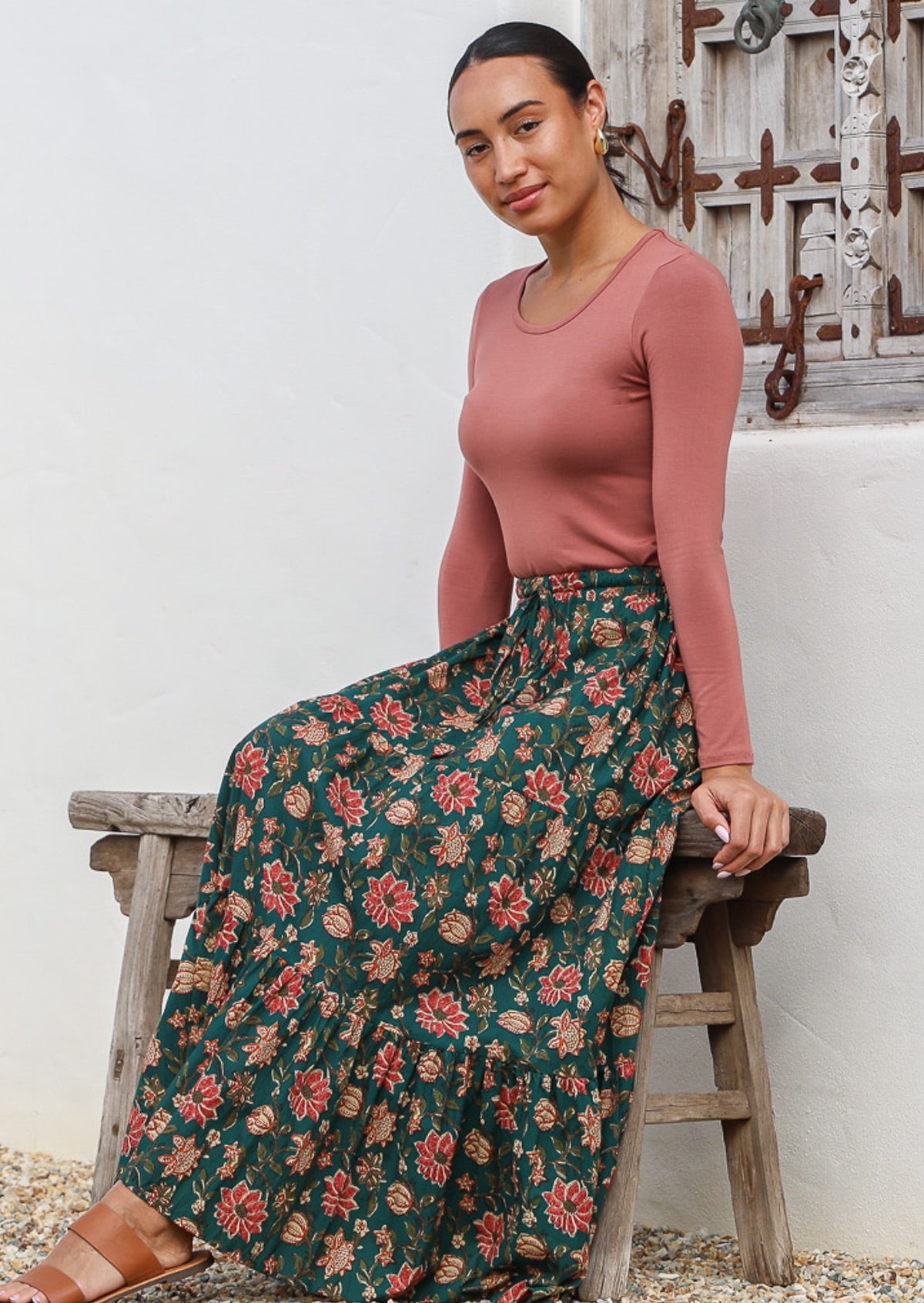 Model sitting on a stool wearing a lightweight boho style cotton maxi skirt with elasticated waistband and drawstring.