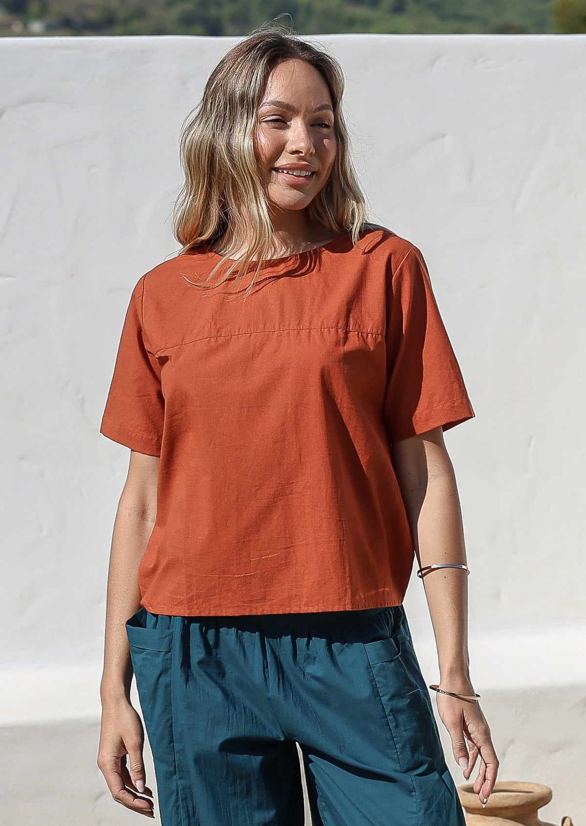 Model wearing a 100% cotton top in rust shade paired with a deep blue pants