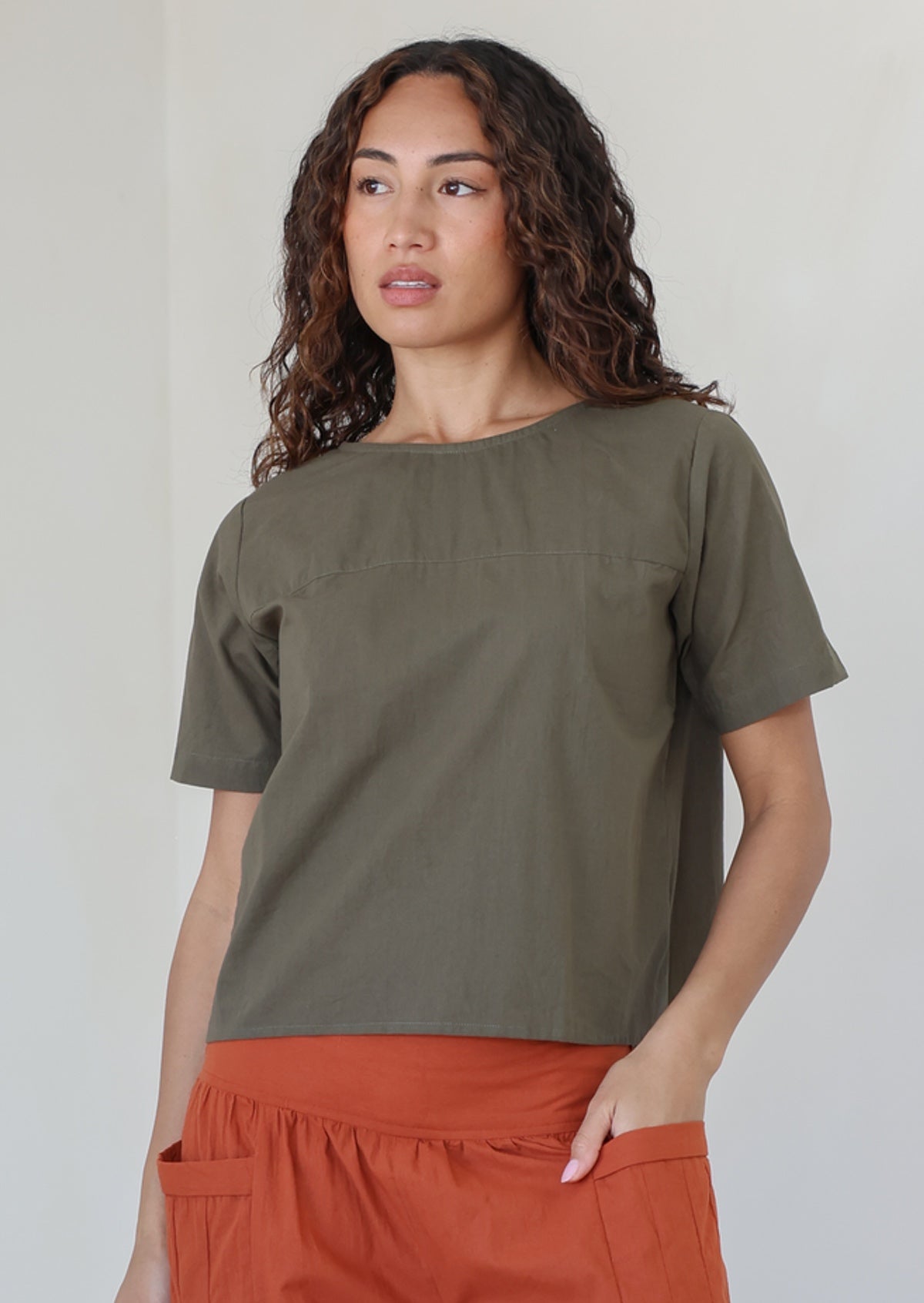 Woman wearing a plain top in olive green shade, 100% cotton top with round neckline