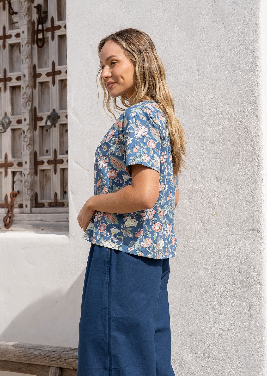 Model wearing a 100 percent cotton loose fit, dusty blue floral top with dark blue cotton pants.