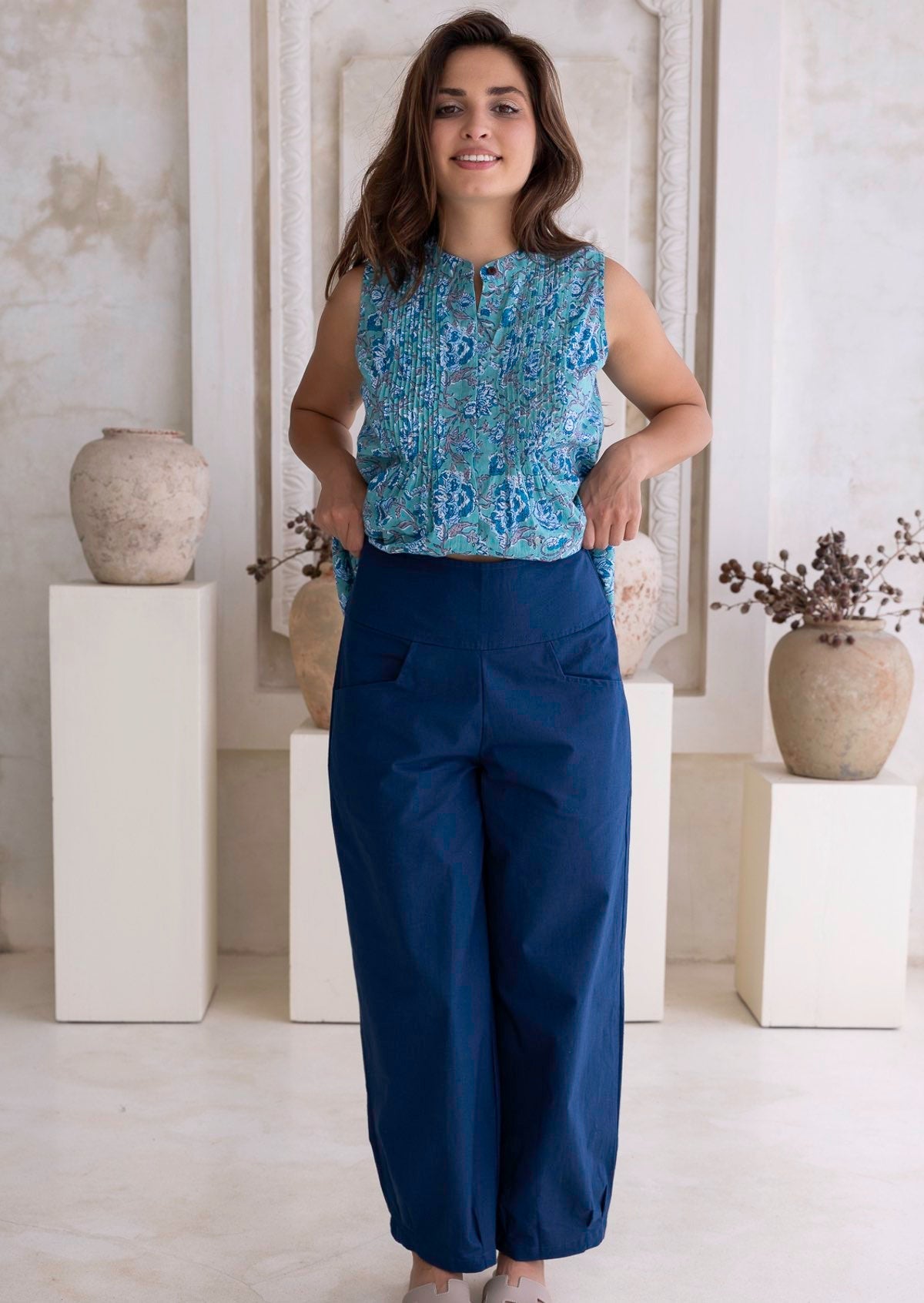Model posing in a sea blue, 100 percent cotton wide leg pants with pleated ankles, pockets and side zipper
