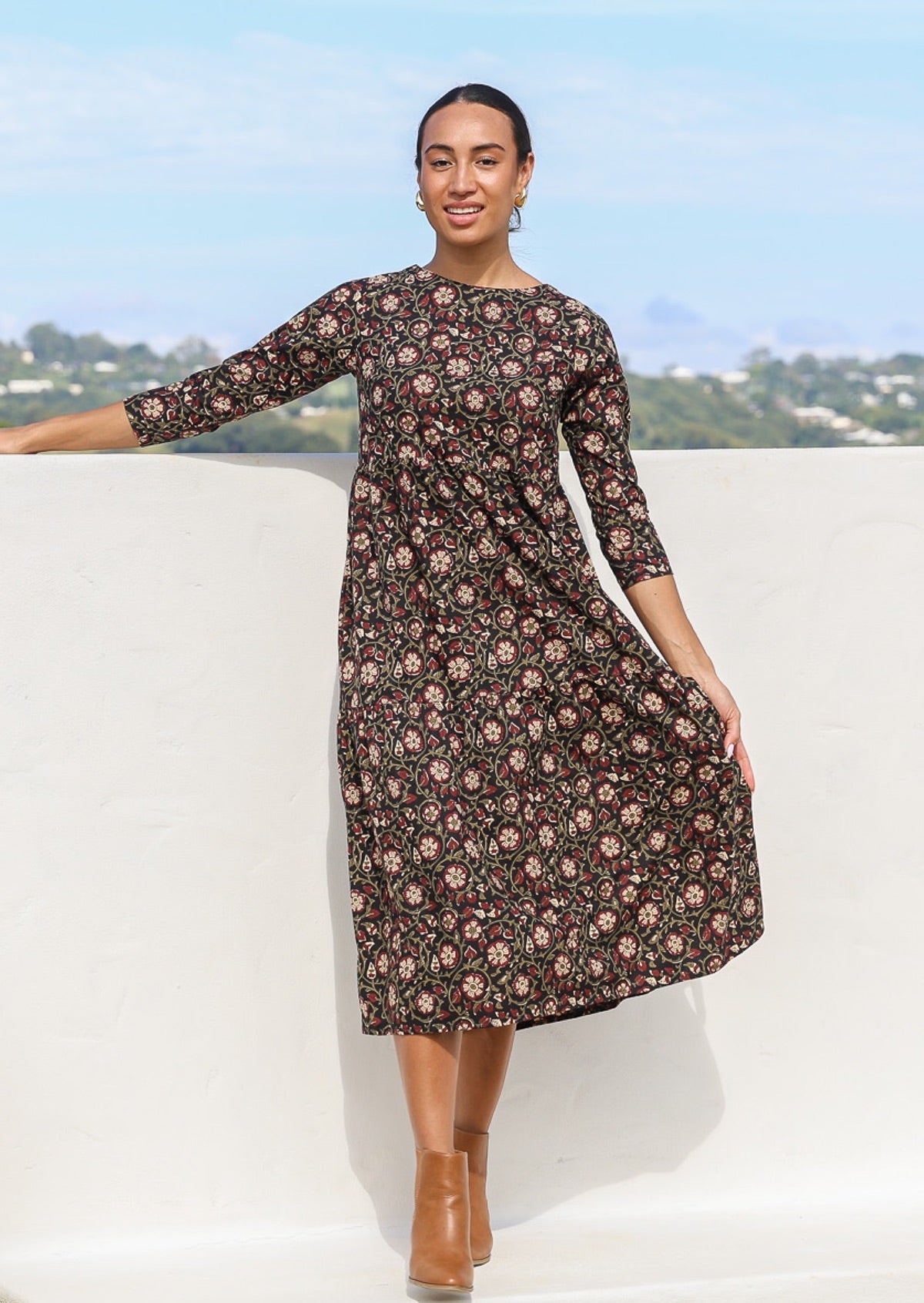 Model wearing a 100% cotton, floral print dress with long sleeves and high round neckline.
