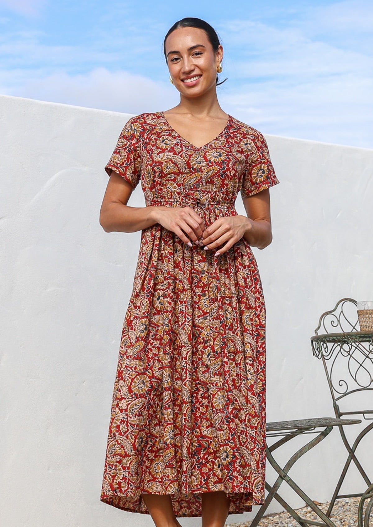 Model wears cotton button through relaxed fit dress with V-neckline and small gathers under the empire waistline.